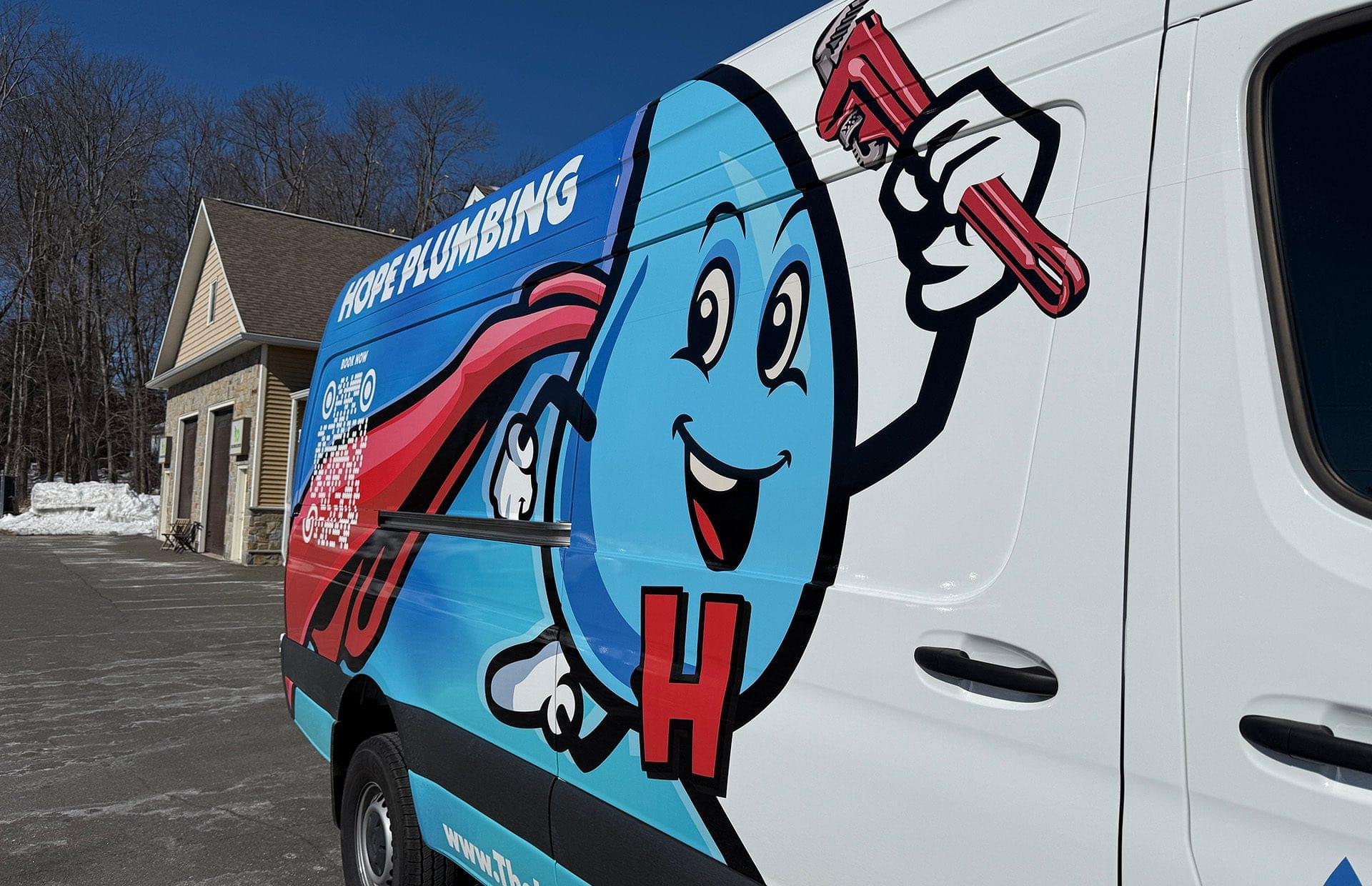 A white 'Hope Plumbing' service van with a large, colorful graphic of a blue water drop mascot holding a red pipe wrench is parked on a snowy suburban driveway.